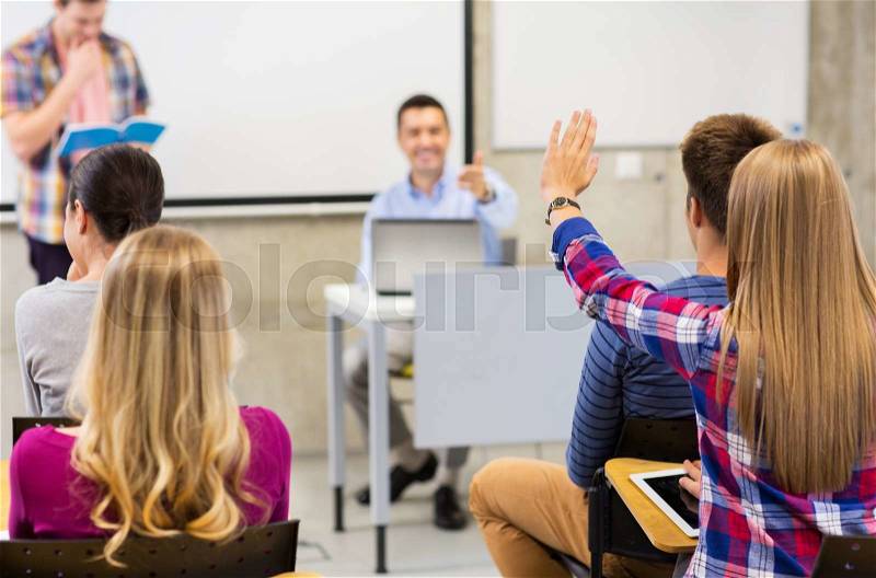 Education, high school, teamwork and people concept - group of students raising hand and teacher in lecture hall or classroom, stock photo