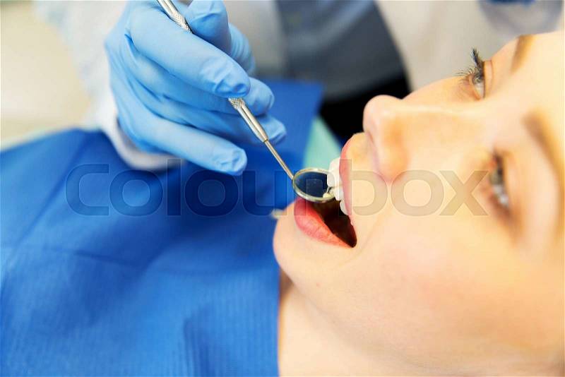 People, medicine, stomatology and dentistry concept - close up of dentist hand with mouth mirror checking female patient teeth up at dental clinic office, stock photo