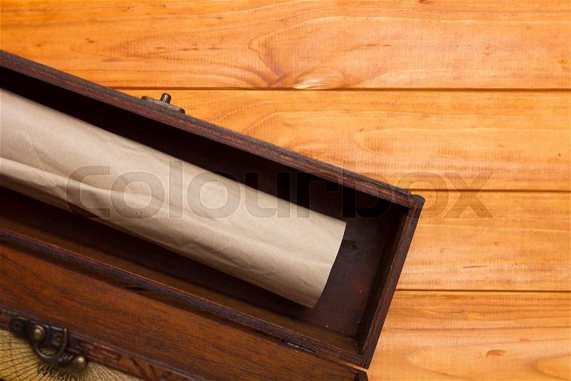 Ancient scroll in a box on a wooden background, stock photo