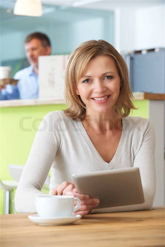 Woman Using Digital Tablet In Cafe, stock photo