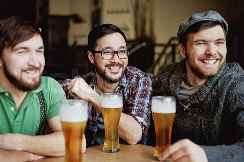Company of happy football fans watching match in pub, stock photo