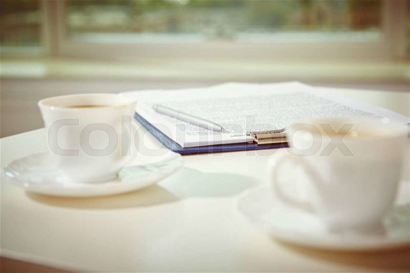 Two cups of coffee and contract with pen on workplace, stock photo
