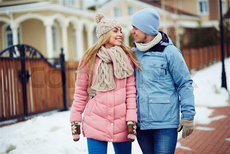 Young sweethearts in winter-wear talking outdoors, stock photo