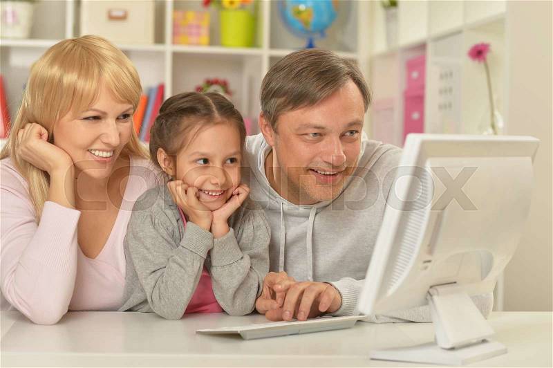 Portrait of happy family playing on computer at home, stock photo