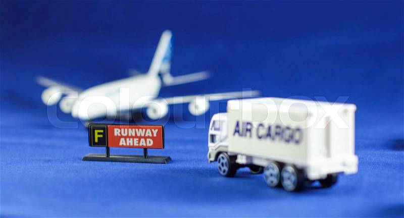 Air Cargo truck heading Runway Ahead sign and defocusing silhouette of an airplane - toy models, stock photo