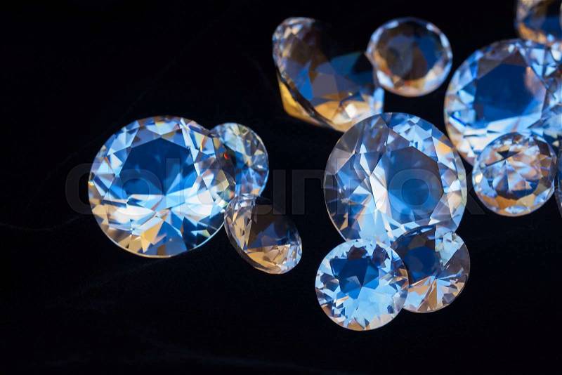 Pile of diamonds on black silk velvet background close up, stock photo