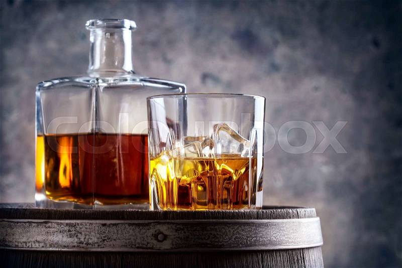 Glass and decanter of whiskey on old wooden barrel, stock photo