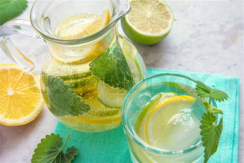 Detox water (lemonade) with lime, lemon and mint in glass jug with copy space, stock photo