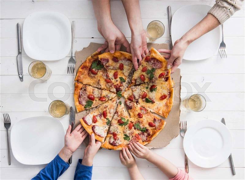 Four hands taking pieces of pizza top view, stock photo