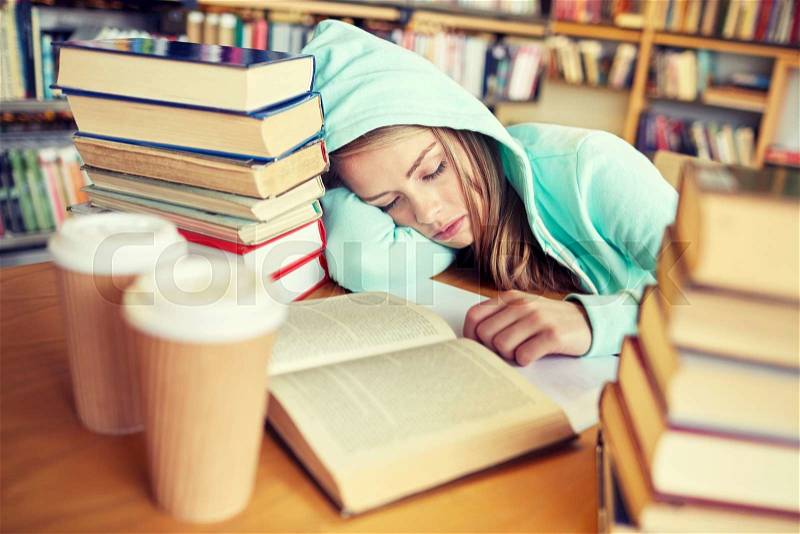 People, education, session, exams and school concept - tired student girl or young woman with books and coffee sleeping in library, stock photo