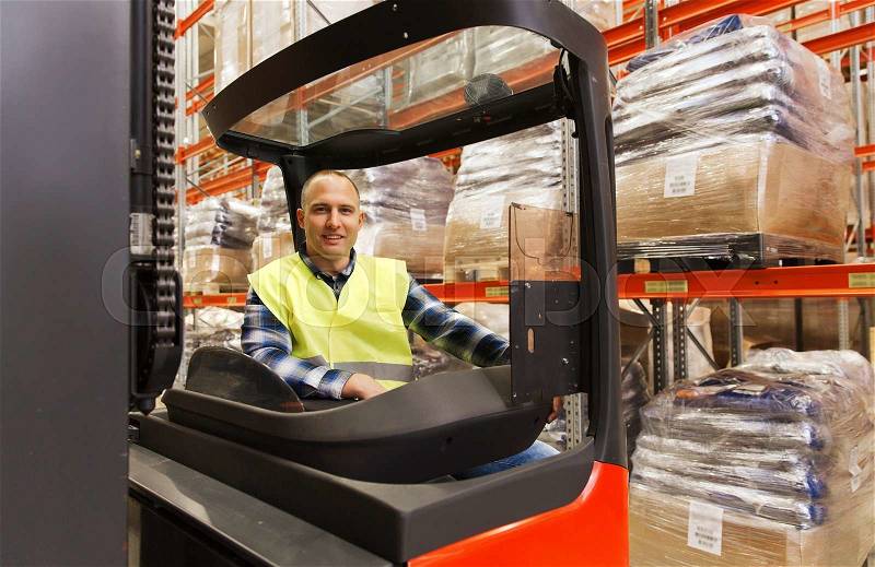Wholesale, logistic, loading, shipment and people concept - smiling man or loader operating forklift loader at warehouse, stock photo
