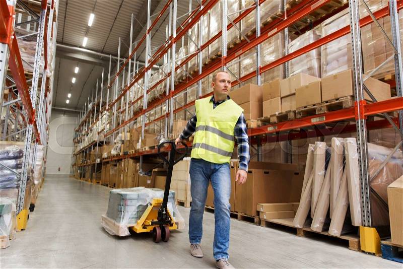 Wholesale, logistic, loading, shipment and people concept - man carrying loader with goods at warehouse, stock photo