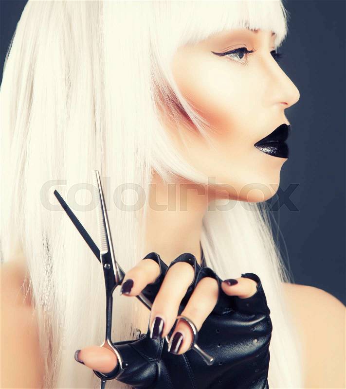 Beautiful blonde woman with black make-up and accessories posing with scissors, stock photo