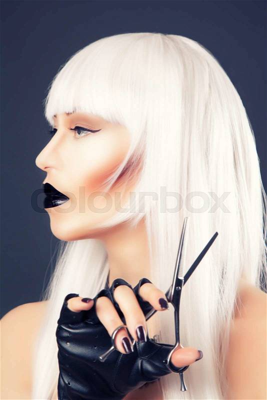 Beautiful blonde woman with black make-up and accessories posing with scissors, stock photo