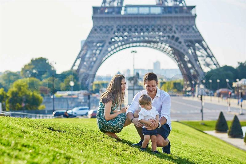 Happy family of three near the Eiffel tower and enjoying their vacation in Paris, France, stock photo