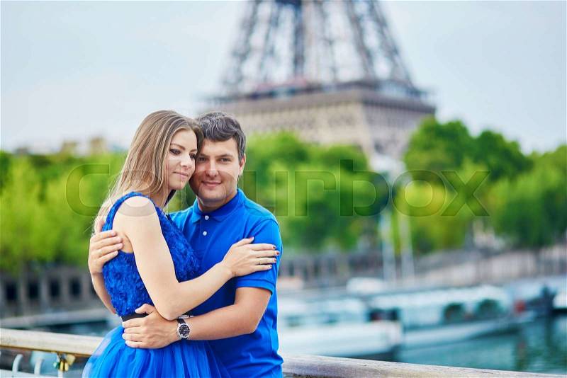 Romantic dating couple on a bridge over the Seine in Paris, Eiffel tower is in the background, stock photo