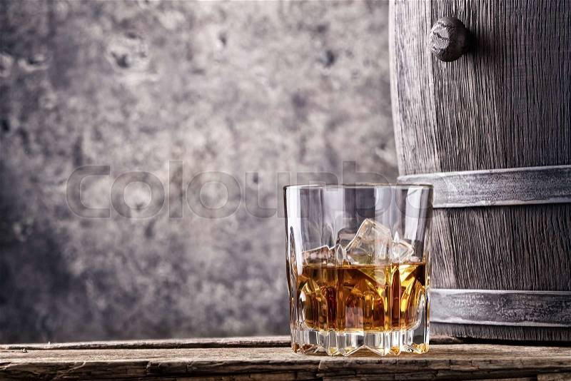 Glass and cask with old whiskey on wooden table, stock photo