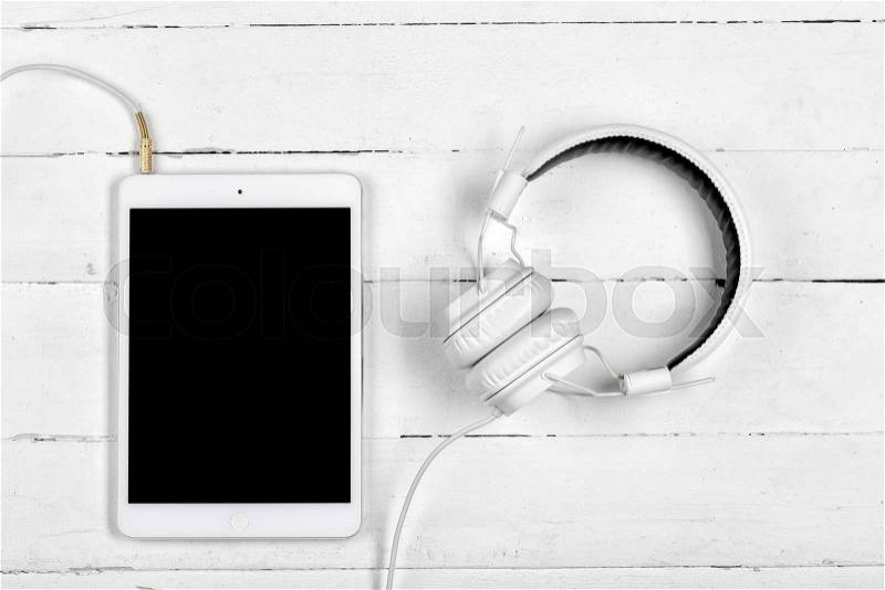 White tablet computer and the white headphones on white boards, stock photo