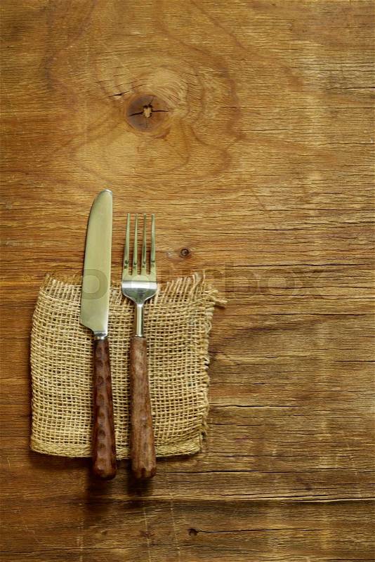 Cutlery (knife and fork) on wooden background, stock photo