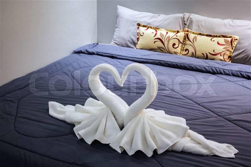 Towel folded in swan shape on bed sheet, stock photo