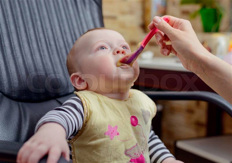 Cute Baby Boy with Porridge Food around his Mouth, Sitting on an Office Chair and Looking Up, stock photo