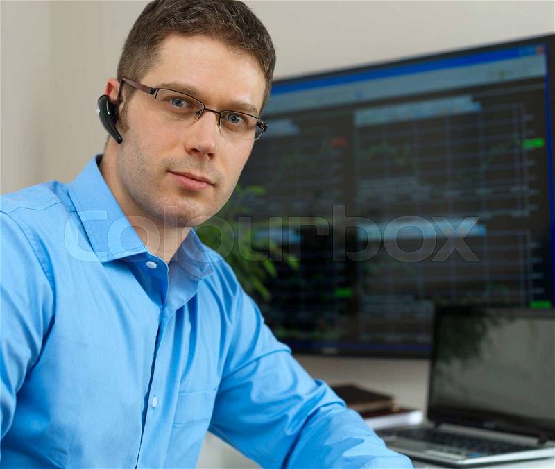 Handsome stock trader in front of computer, stock photo