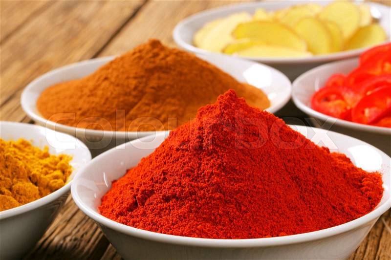 Bowls of curry powder, paprika, ground cinnamon, sliced ginger root and red pepper, stock photo