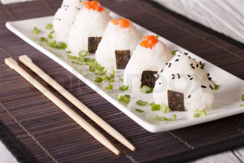 Japanese onigiri rice balls stuffed with salmon and sesame close-up on a white plate. Horizontal , stock photo