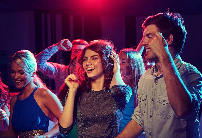 Party, holidays, celebration, nightlife and people concept - group of happy friends dancing in night club, stock photo