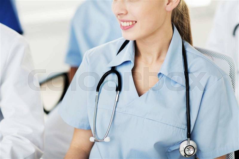 Education, profession, people and medicine concept - close up of happy female doctor with stethoscope at seminar or hospital, stock photo