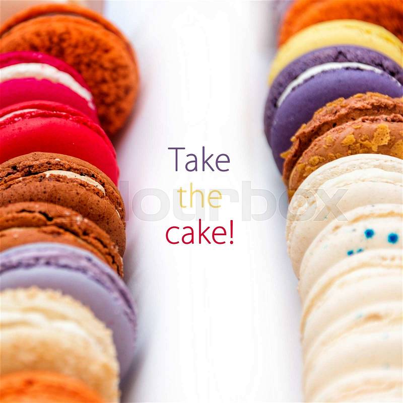 Traditional french colorful macaroons in a rows in a box with words Take The Cake, stock photo