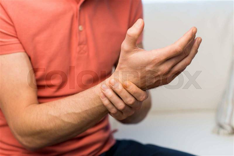 People, healthcare and problem concept - close up of man suffering from pain in hand oe wrist at home, stock photo