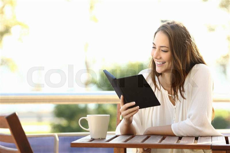 Woman relaxed reading a book in an ebook reader in a bar or at home, stock photo