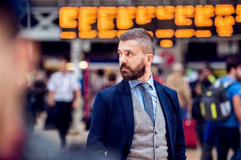 Hipster businessman in suit waiting at the crowded London train station, stock photo