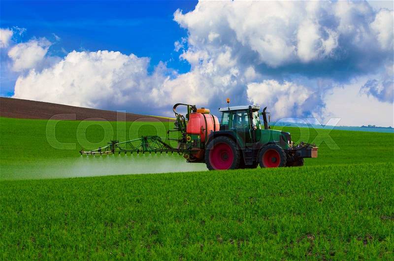 Farm machinery spraying insecticide to the green field, agricultural natural seasonal spring background, stock photo