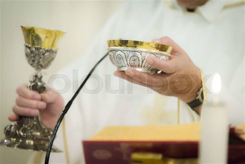 Priest celebrating the communion with goblet and holy bread, stock photo