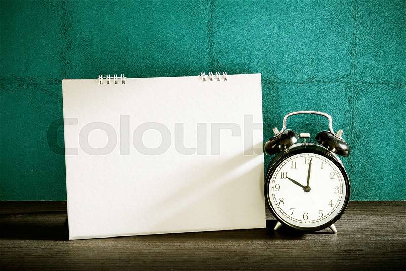 Stillife of desk calendar with alarm clock on wood table. Vintage filtered, stock photo