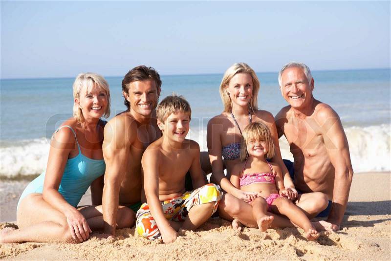 Three generation family pose on beach, stock photo