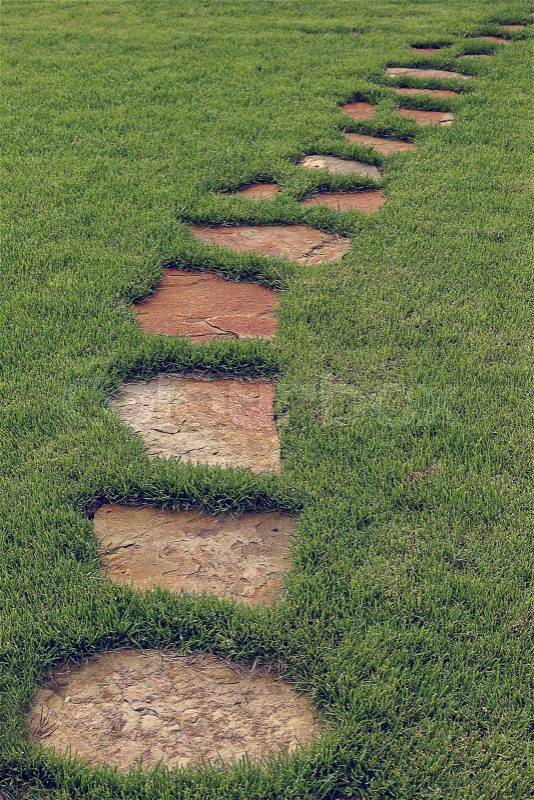 Stone path in green grass as a background, stock photo