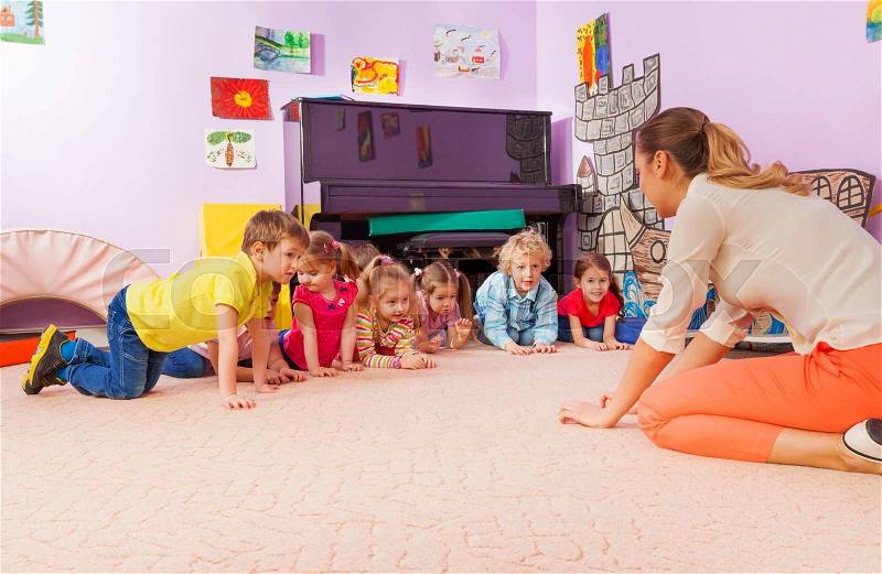 Large group of kids on all fours repeat after teacher in kindergarten playing active game, stock photo