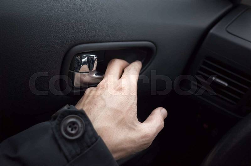 Male hand opens the inner door handle, modern car interior, stock photo