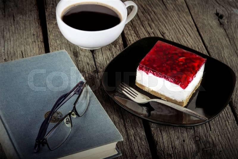 Vintage book reading cup of coffee and cheese cake on grungy wooden background, stock photo