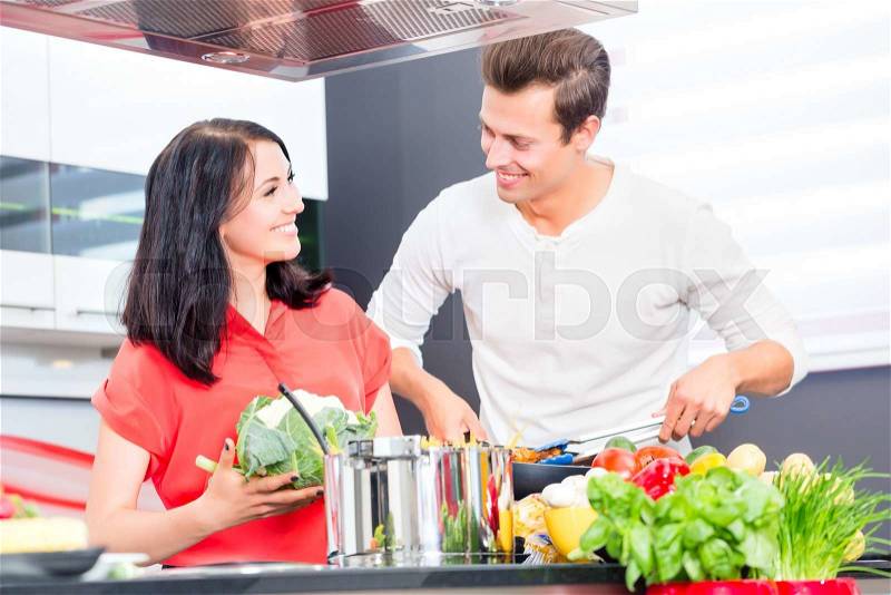 Woman and man cooking meat in domestic kitchen, stock photo