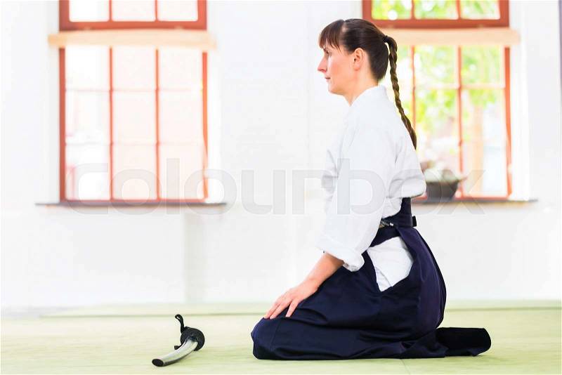 Woman sitting on mats while Aikido training in martial arts school , stock photo