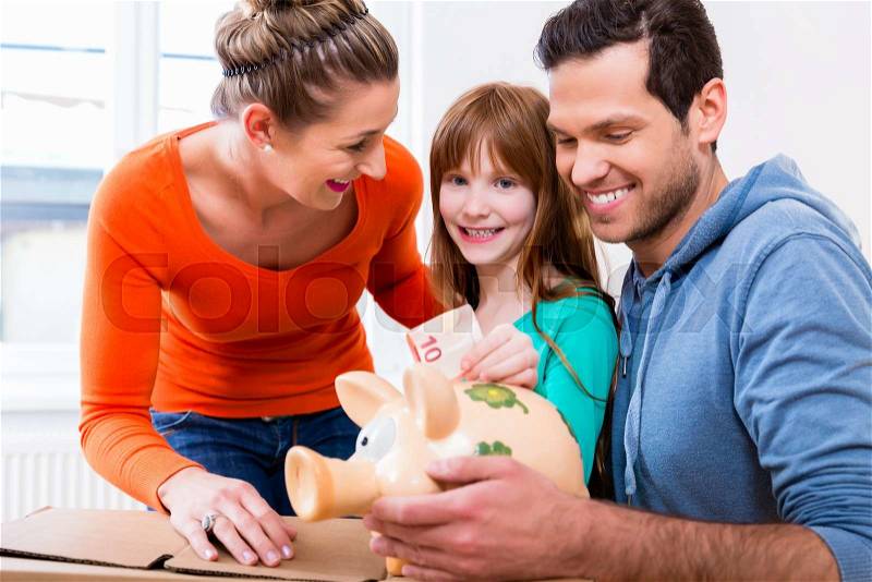 Family saving money by moving house putting bank note in piggybank, stock photo