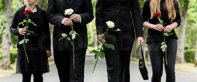Torso of family on cemetery mourning holding red and white roses in hands, stock photo