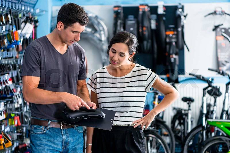 Woman buying parts in bike shop, stock photo
