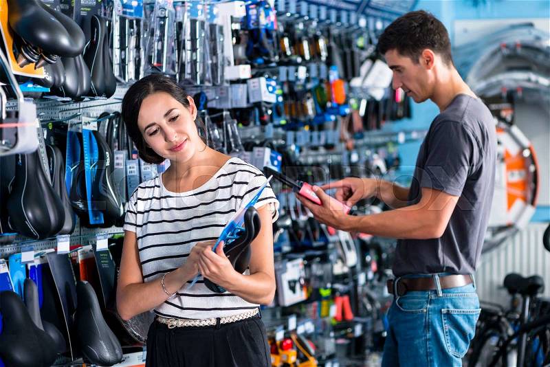 Woman buying parts in bike shop, stock photo