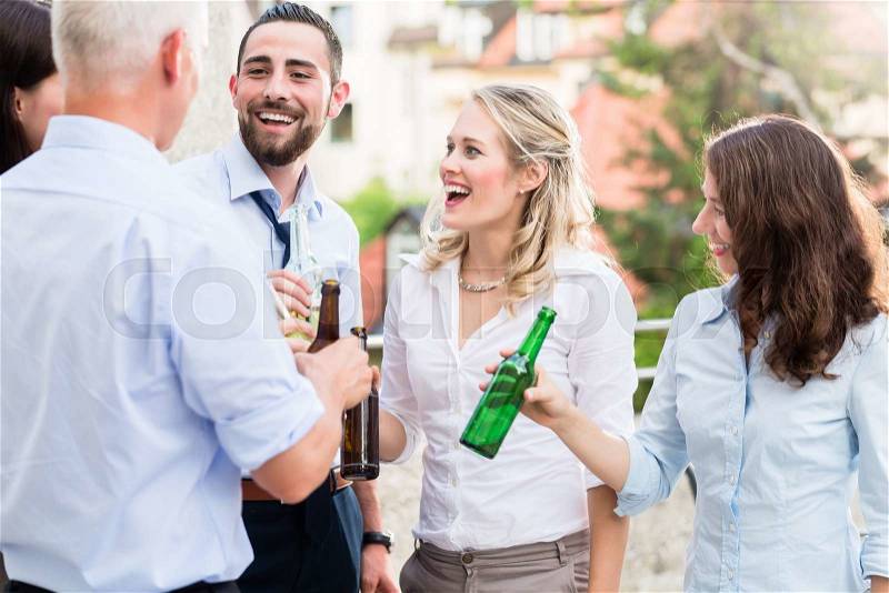 Office colleagues drinking beer after work on terrace celebrating, stock photo