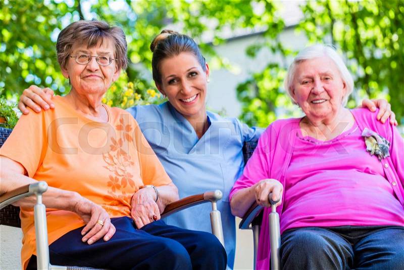 Geriatric nurse having chat with senior women, stock photo